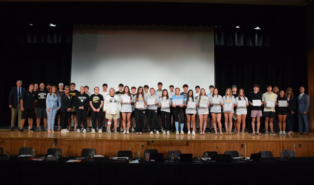 students standing on stage holding certificates